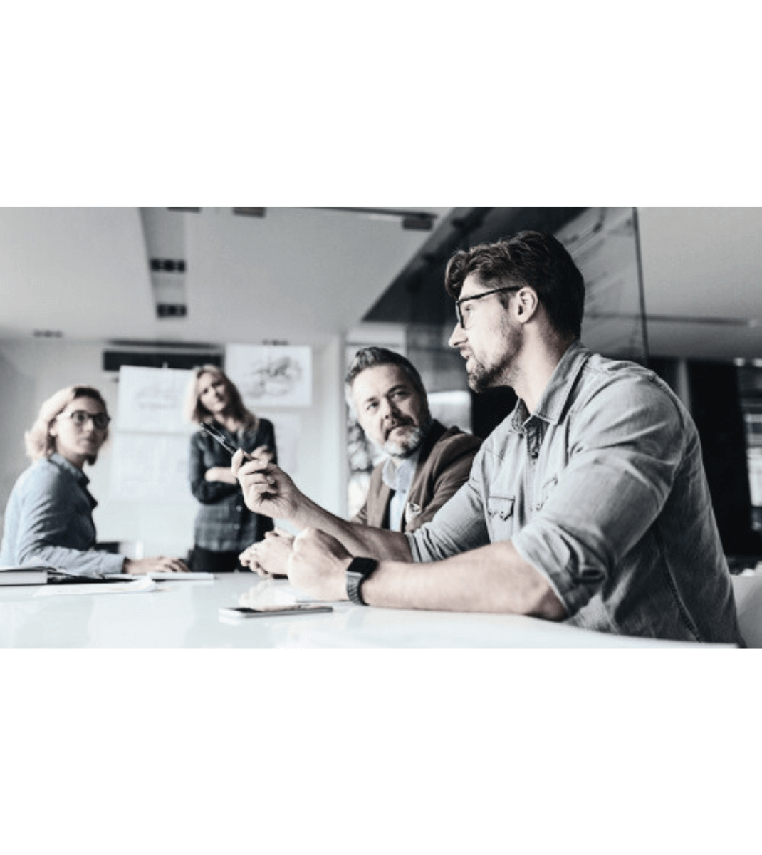 Team of professionals engaged in a discussion around a conference table in a modern office setting.