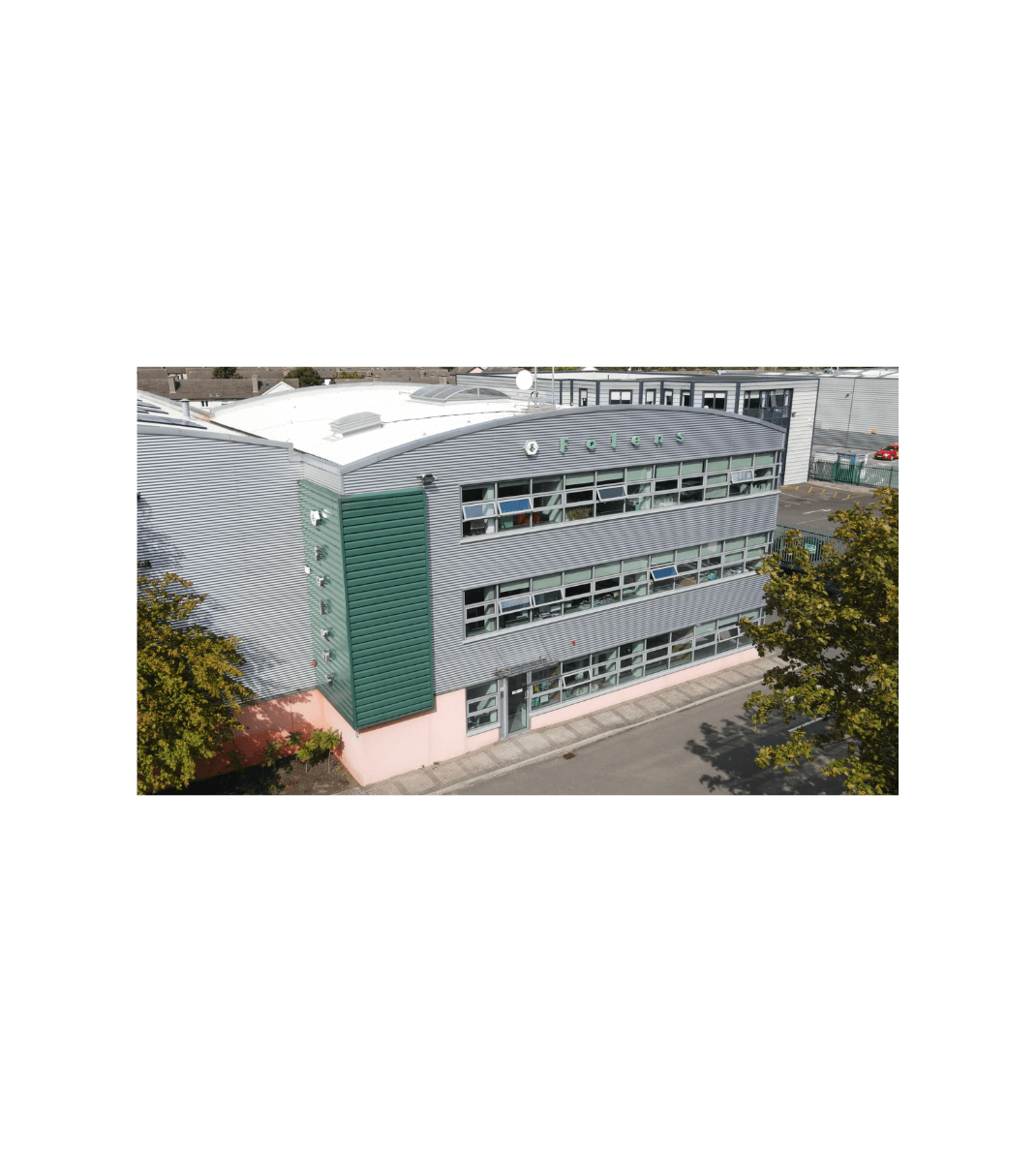 Folens headquarters building with modern grey and green exterior, large windows, and company name displayed near the roofline.