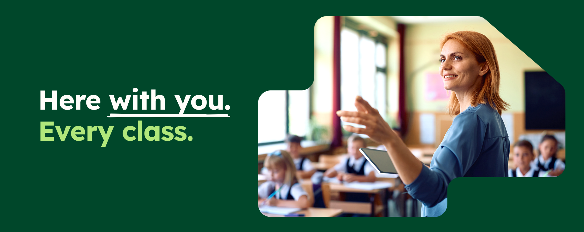 Smiling teacher with a tablet gestures to uniformed students in class, beside the text “Here with you. Every class.”